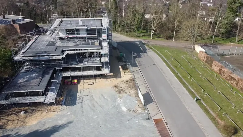 Drone view of a new building under construction beside a road.
