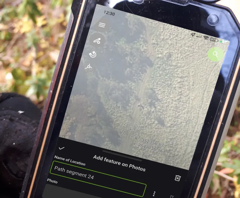 QField on a phone in the field, with the survey map and a form open.